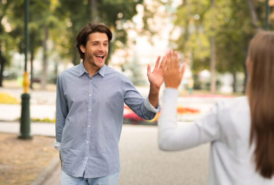 Man Waving Hello Gesture Meeting Female Friend Walking Outdoors