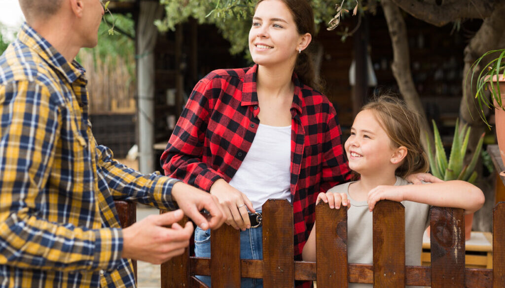 Man, woman and girl talking near fence