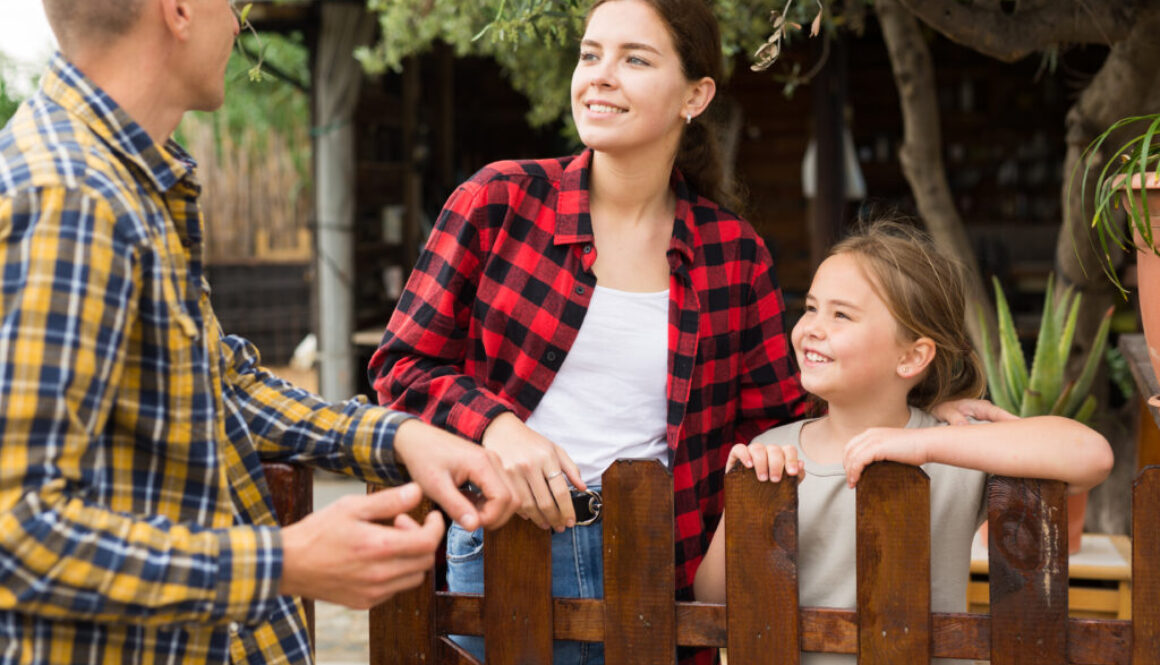 Man, woman and girl talking near fence