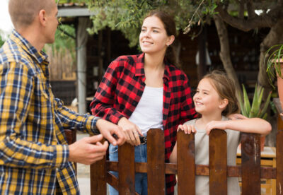 Man, woman and girl talking near fence